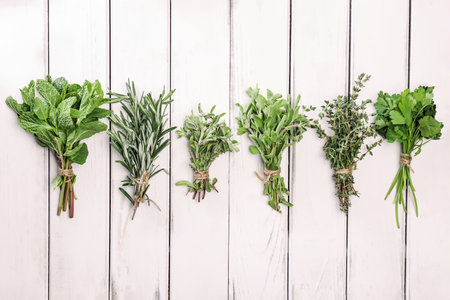Bunches of fresh green herbs on white wooden table, top viewの写真素材