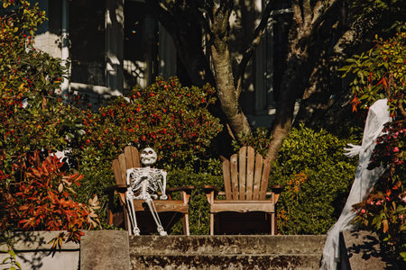 Traditional Halloween decor outside of the house, skeleton sitting on the benchの写真素材