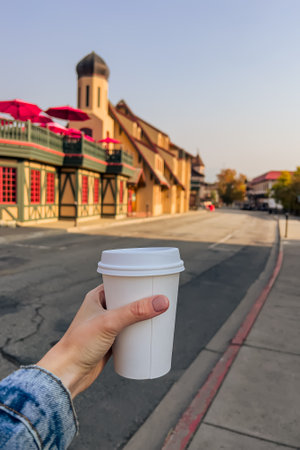 Woman holding a cup of coffee close-up with a blurred town on the backgroundの写真素材
