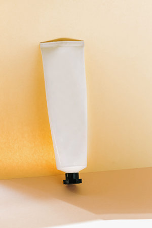 White cosmetic cream container on pale neutral background. Tube mock-up