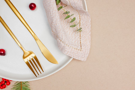 Plate with golden napkin and cutlery, minimal Christmas table setting, top viewの写真素材