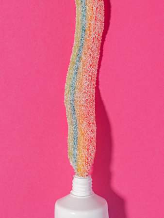 Rainbow tooth paste on pink background. Creative concept.の写真素材