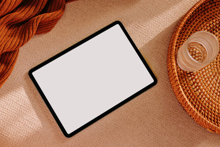 Tablet with blank screen lying on the light couch surface. Device mock-up in neutral tonesの写真素材