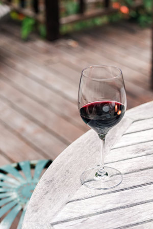 Glass of red wine standing on the wooden table on the patio