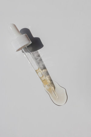Pipette with serum, oil or vitamin essence isolated on white background, natural sunlight with harsh...