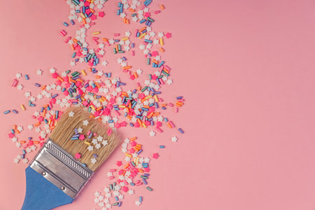Star shaped Sugar sprinkles and paint brush on pink background, creativity and artistry conceptの写真素材