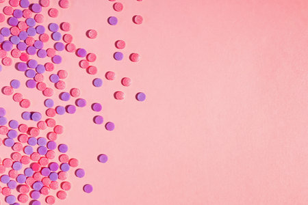 Pink and purple sugar sprinkles on pink background with copy space, party backdropの写真素材