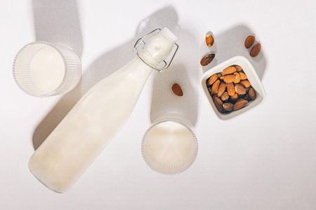 Almond milk on white table in natural light. Dairy alternative vegan milk