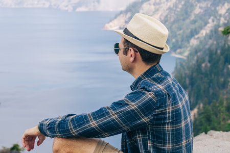 Man in a hat looking in a distance on a beautiful lake, summer travelの写真素材