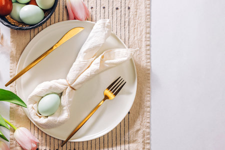 Easter themed table setting, with napkin folded in shape of a rabbit and blue egg, top viewの写真素材