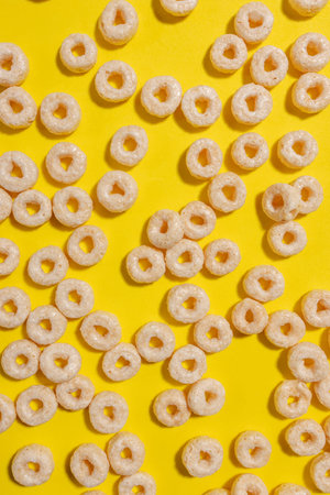 Circle shape cereals on bright yellow background, top view