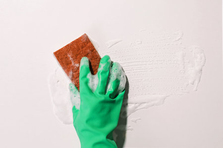 Hand in green rubber glove wiping a foam on the glass, spring cleaning conceptの写真素材