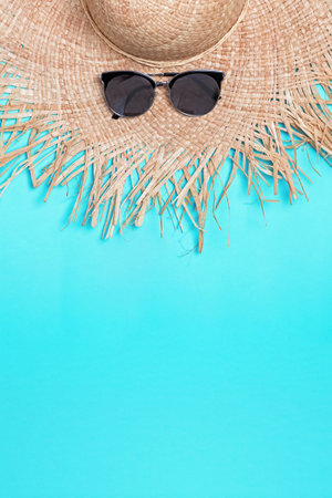 Straw hat with wide fields and sunglasses on blue background with copy spaceの写真素材