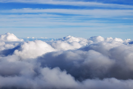 White puffy clouds fill the lower half of the frame, with blue skies visible above them