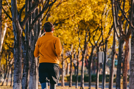 A person jogging in a suburban neighborhood with vibrant autumn foliage on a sunny morningの写真素材