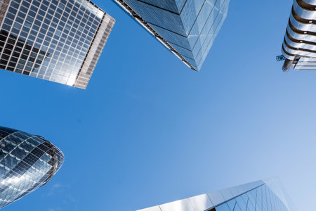 Modern skyscrapers in London downtown reaching towards a clear blue sky in a busy urban setting, business backgroundの写真素材