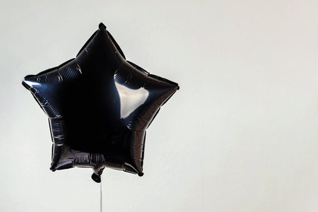 Black balloon in the shape of a star floating against a plain background, background with copy spaceの写真素材
