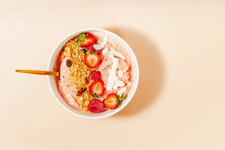 Healthy smoothie bowl topped with sliced strawberries, granola and coconut chips, top viewの写真素材