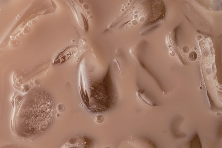Creamy iced beverage or coffee with droplets and ice cubes in mocha mousse colorの写真素材