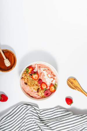 Strawberry smoothie bowl topped with granola, berries and honey, top viewの写真素材