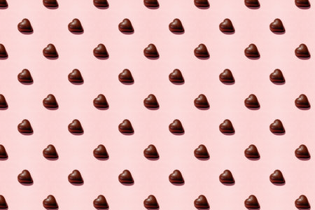 Heart-shaped chocolate pieces arranged on a soft pink background, Valentine's day backdropの写真素材