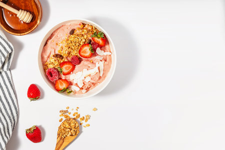 Delicious smoothie bowl with strawberries, topped with granola and coconut chips, healthy breakfastの写真素材