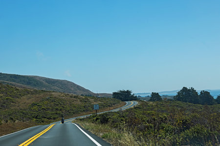 Winding road through coastal landscape with clear skies and distant ocean view on the California coastの写真素材