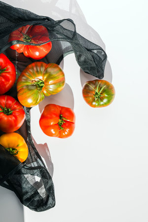 Fresh summer Heirloom Tomatoes in Reusable Mesh Bag in natural lightの写真素材