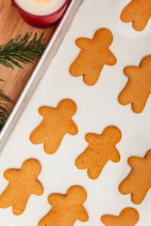 A batch of freshly baked gingerbread man cookies on a parchment-lined baking tray.