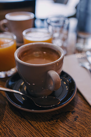 A warm, inviting scene featuring a cup of coffee on a wooden table, accompanied by glasses of orange juice.の写真素材