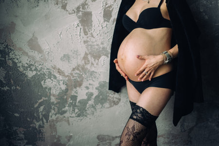 pregnant woman hugging belly in underclothes lace stockings hugging