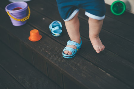 small kid in one shoes in the yard near house playing