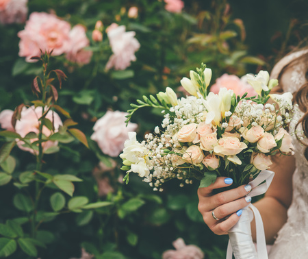 bride is holding beautiful wedding bouquet in the parkの写真素材