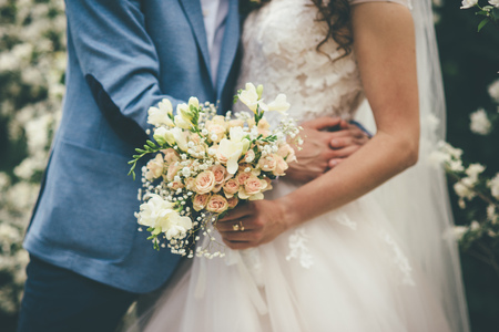 Wedding bouquet in hands of groom in wedding day. Bridal couple huggingの写真素材