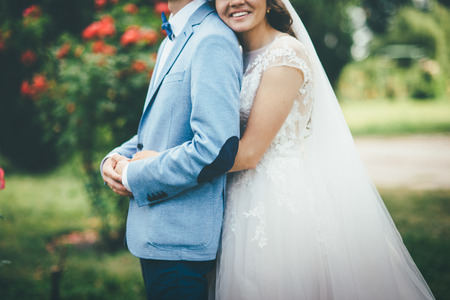 beautiful loving couple newlyweds hugging in wedding dress and blue suitの写真素材