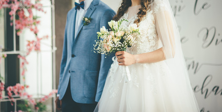 bride and groom walking together with bouquet in hands in dress and blue suitの写真素材