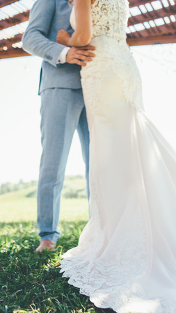 beautiful couple in white wedding dress and blue trousers is hugging in summer wedding dayの写真素材