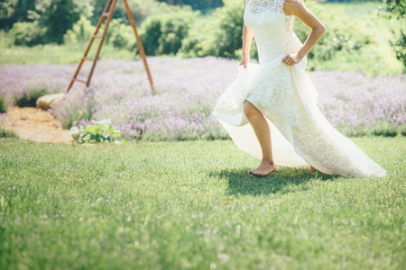 woman is running on the grass in wedding dress sunny dayの写真素材