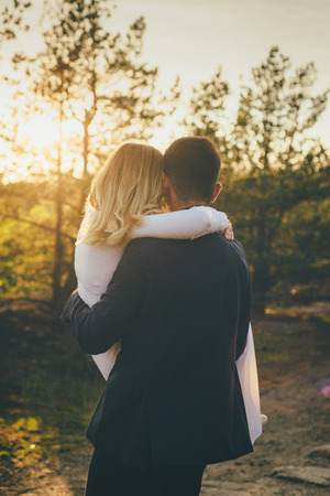 Just married couple hugging white wedding dress and blue costume sunsetの写真素材