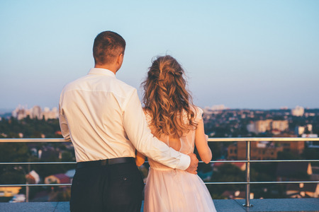 Amazing wedding couple standing in front of evening cityscape and huggingの写真素材