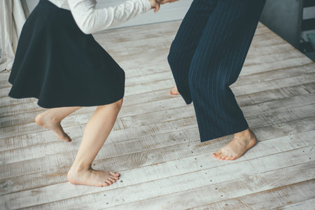Pair of two girls dance barefoot on the white wooden floor and share positive vibes