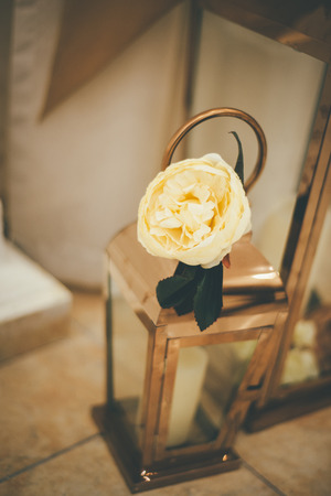 Wedding metal lantern with creamy rose on top as cozy decorationの写真素材