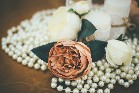 Detailed vintage composition of wedding roses, peral lace and candles on wooden tableの写真素材