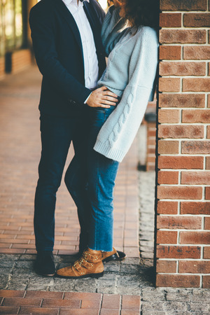 Amazing stylish couple stands near the red brick wall and huggingの写真素材