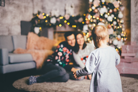 Back view of the baby watching his parents sitting near the decorated Christmas tree, partly focused imageの写真素材