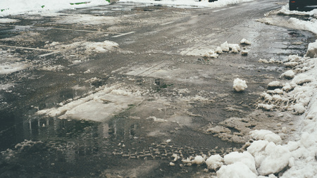 Closeup image of the dirty brown and white snow with car tracks on itの写真素材