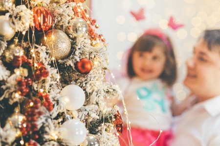 Christmas tree in front and cute father and daughter blurred in the backgroundの写真素材