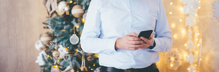 Man Using Mobile Phone In Room Decorated For Christmasの写真素材