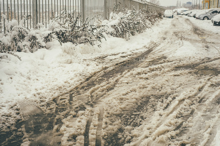 Closeup image of the dirty brown and white snow with car tracks on itの写真素材