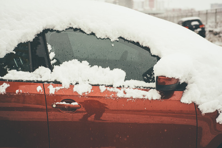 Cide view of the red car in closeup, covered in fresh fluffy snowの写真素材